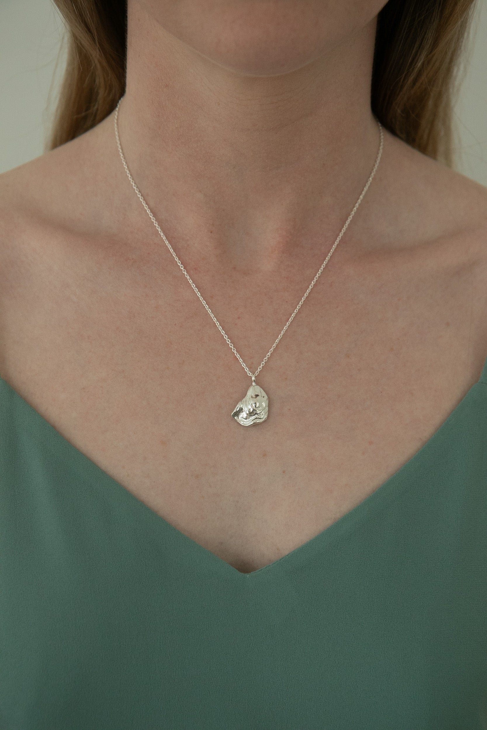 Model wears sterling silver oyster lid necklace, the larger life-size version