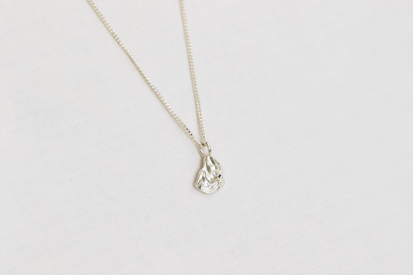 Small silver oyster pendant necklace on a light background
