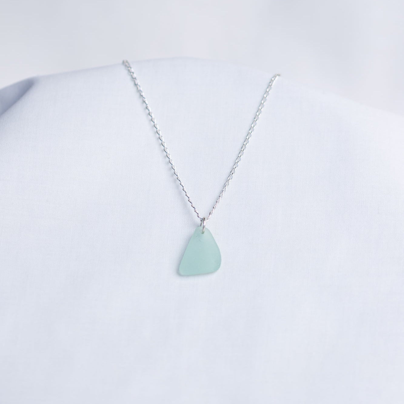 Necklace with a light blue sea glass pendant on a white background