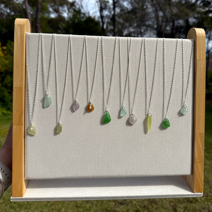 silver necklaces with sea glass and pearls on display stand outside